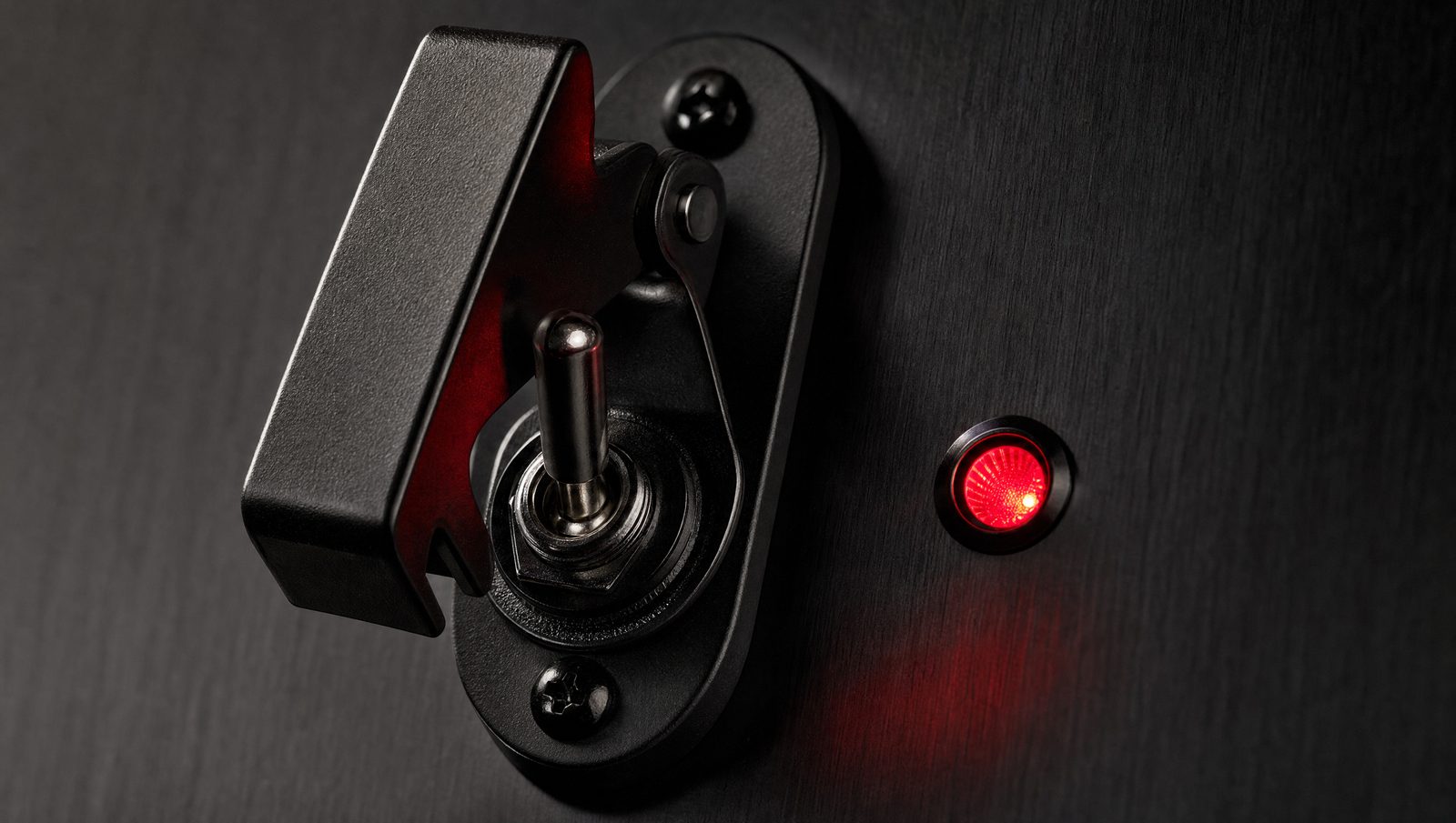 A covered safety toggle switch next to a red indicator light